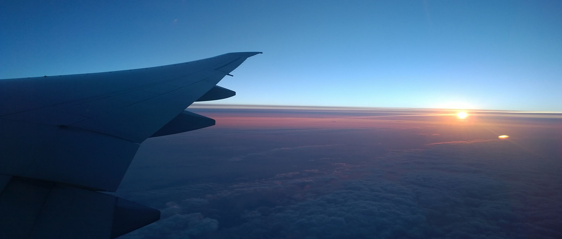 Sunrise seen from an aircraft window above the clouds